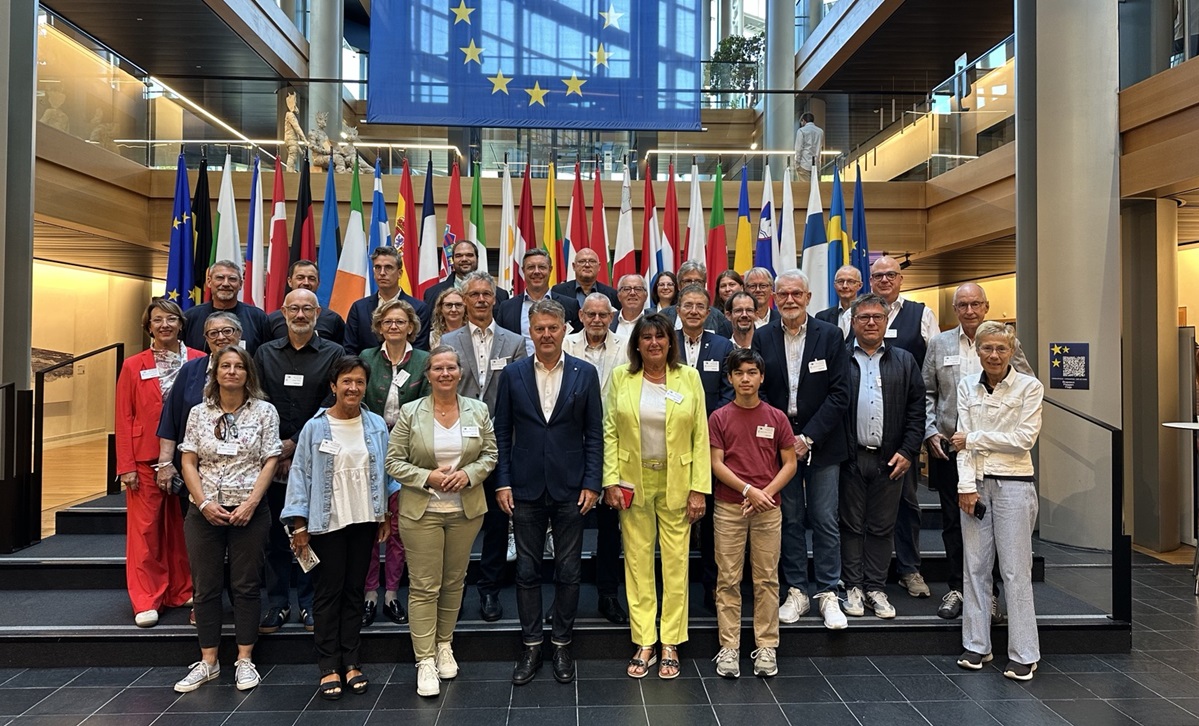 Gruppenbild: Die Districtsrat-Delegation steht im EU-Parlament vor EU-Fahnen