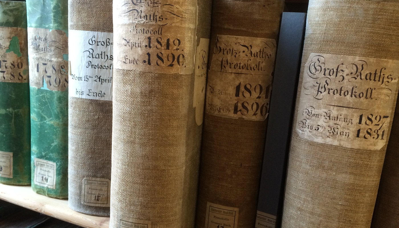 Mehrere Bände Grossratsprotokolle auf einem Gestell im Staatsarchiv.