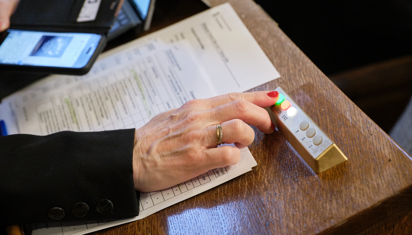 Eine Hand drückt auf dem Abstimmungsgerät den Nein-Knopf.