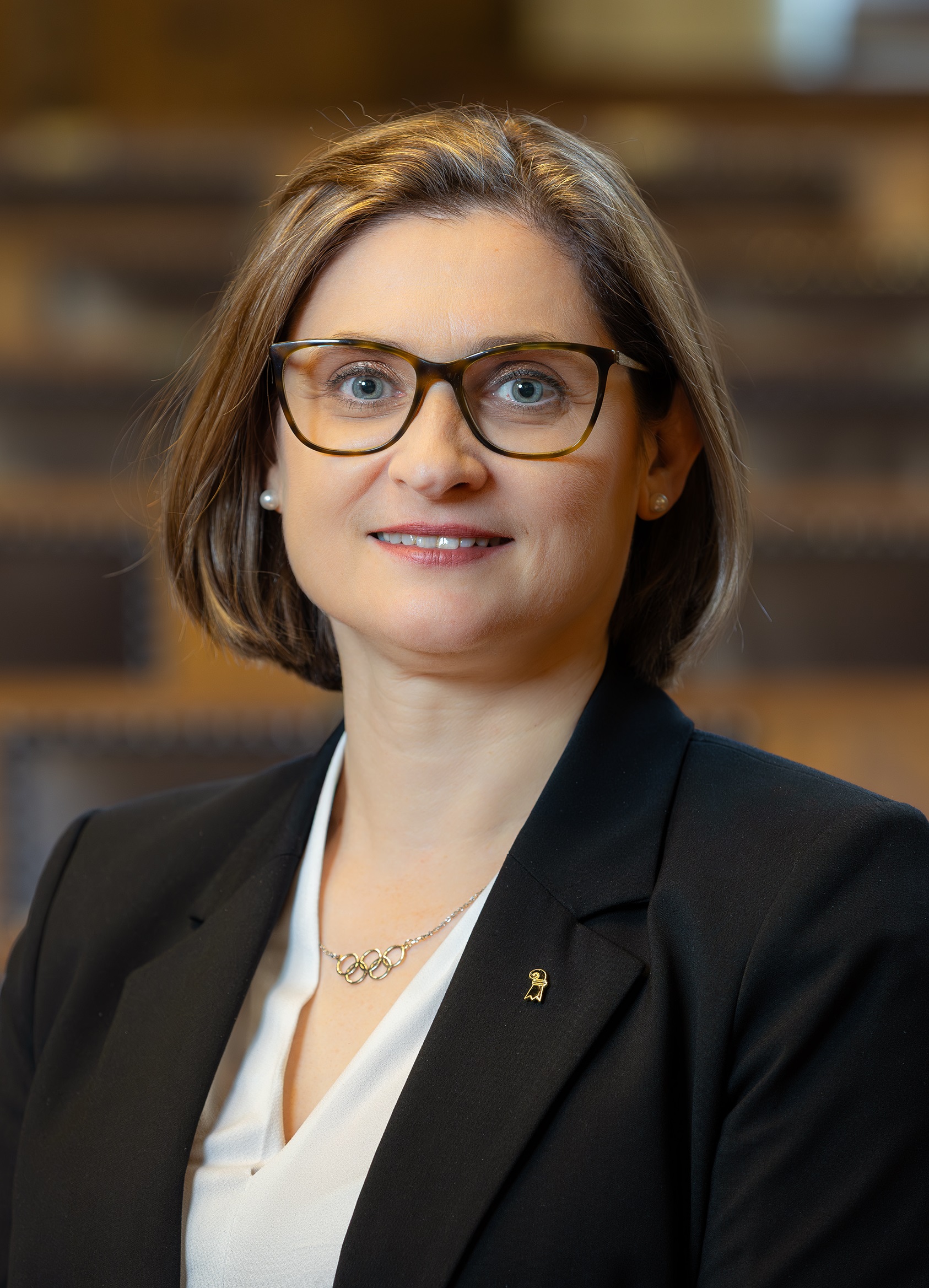 Grossratspräsidentin Gianna Hablützel im Porträt, im Hintergrund sind die Sitzreihen des Grossratssaals angedeutet.