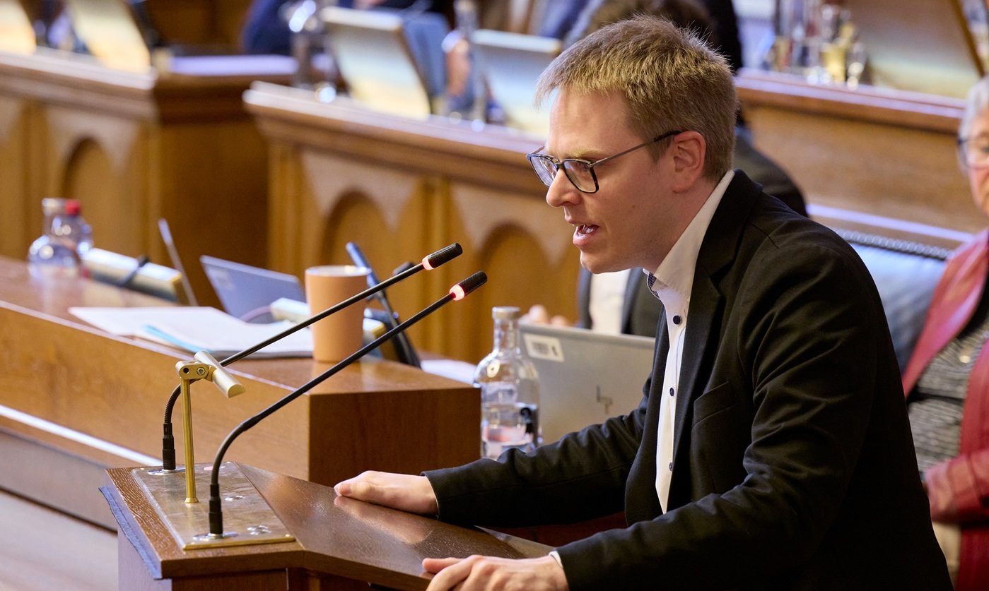 Ein Grossrat spricht vorne am Redepult ins Mikrofon